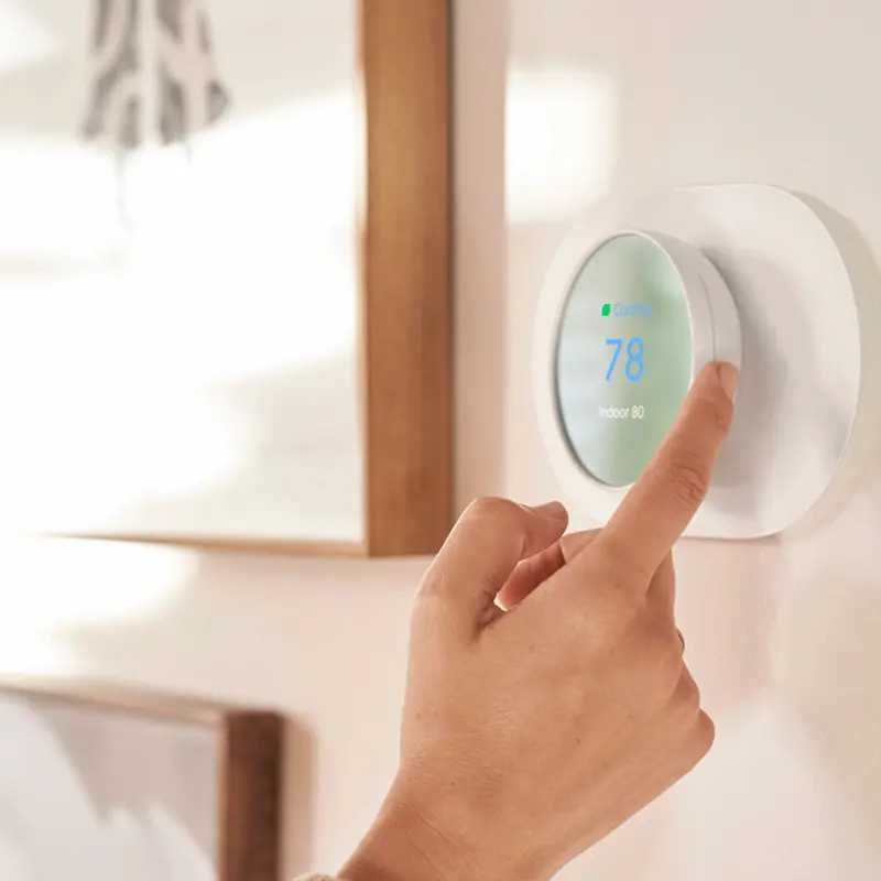 Homeowner adjusting a modern smart thermostat on the wall of a contemporary living room for optimal energy efficiency